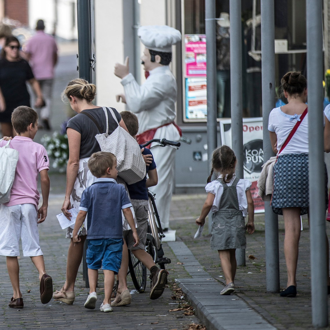 Een gezin met kinderen wandelt door de winkelstraten van Meerssen