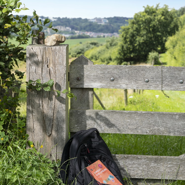 Viabelgica gids liggend op een tas met uitzicht over heuvelland